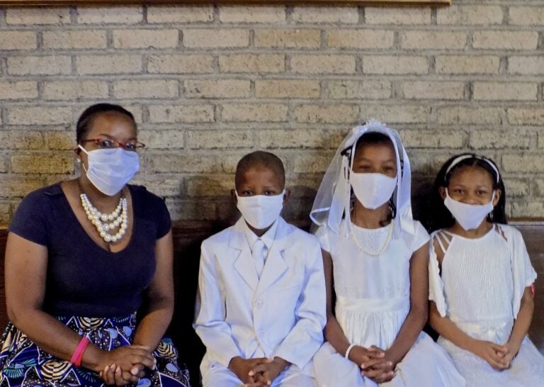 Jennifer Ballard (left) accompanies her children (from lert) Allan and Allyson Ballard, and their friend Joselyn Turner, as they get ready for their First Holy Communion. (Ximena Conde/WHYY News)