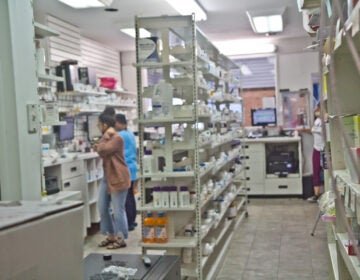 Workers inside a small pharmacy filling scripts