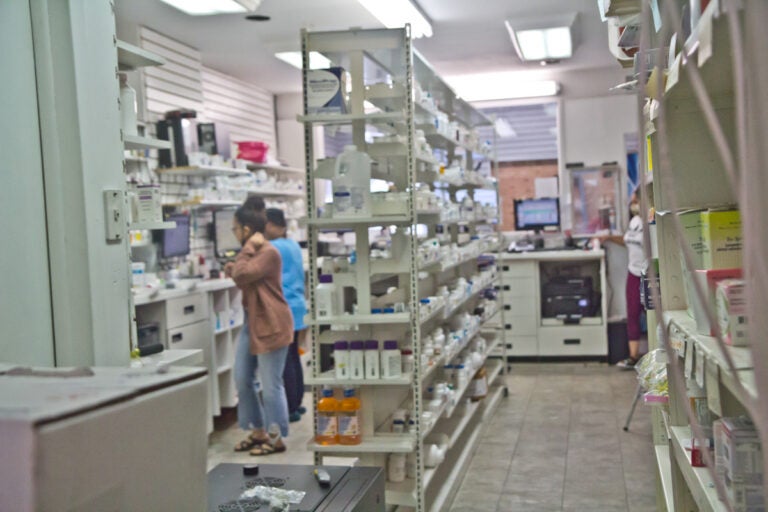 Workers inside a small pharmacy filling scripts