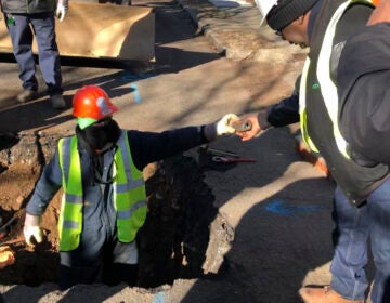 A worker hands a piece of lead pipe to a colleague as they work to remove water service lines Thursday, Jan. 9, 2020 in Trenton, N.J. The city announced it is replacing 37,000 lead pipes over five years as part of an an effort to remove the potentially harmful pipes. (AP Photo/Mike Catalini)