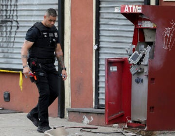 A member of the Philadelphia bomb squad surveys the scene after an ATM machine was blown-up at 2207 N. 2nd Street in Philadelphia, Tuesday,  June 2, 2020.  (David Maialetti/The Philadelphia Inquirer via AP)