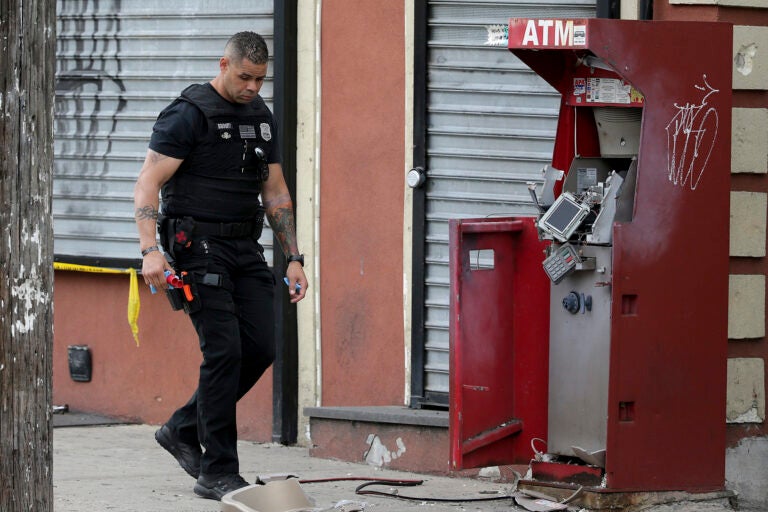 A member of the Philadelphia bomb squad surveys the scene after an ATM machine was blown-up at 2207 N. 2nd Street in Philadelphia, Tuesday,  June 2, 2020.  (David Maialetti/The Philadelphia Inquirer via AP)