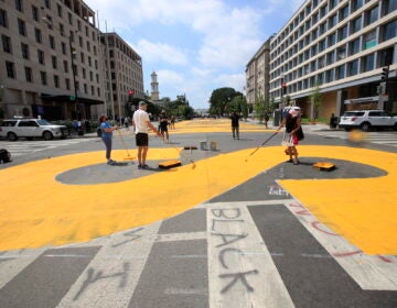 City workers and activists paint the words Black Lives Matter in enormous bright yellow letters on the the street leading to the White House, Friday, June 5, 2020, in Washington.(AP Photo/Manuel Balce Ceneta)