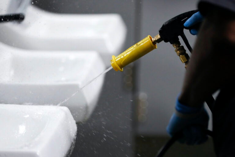 Des Moines Public School employee Daniel Brown sanitizes a sink in a bathroom at Central Campus high school, Thursday, March 19, 2020, in Des Moines, Iowa. (AP Photo/Charlie Neibergall)