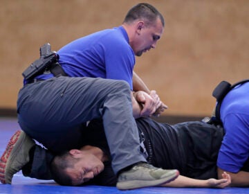 In this June 4, 2020, photo, Brandon Wilson, upper left, an instructor at the Washington state Criminal Justice Training Commission facility in Burien, Wash., restrains fellow instructor Ben Jia, lower left, during a demonstration for The Associated Press on takedown and restraint techniques taught to law enforcement officers as part of the more than 700 hours of training police and other officers are required to to through in the state. Police training has been under scrutiny again since the death of George Floyd, a black man who died after being restrained by Minneapolis police officers. (AP Photo/Ted S. Warren)