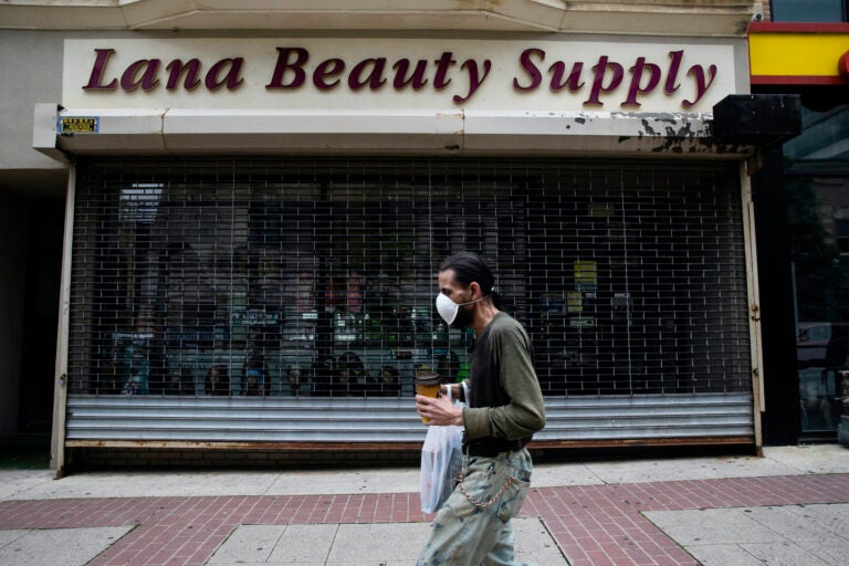 A shopper in a mask walks in front of a shuttered store in downtown Allentown, Pa., on Friday, May 29, 2020. (AP Photo/Matt Rourke)