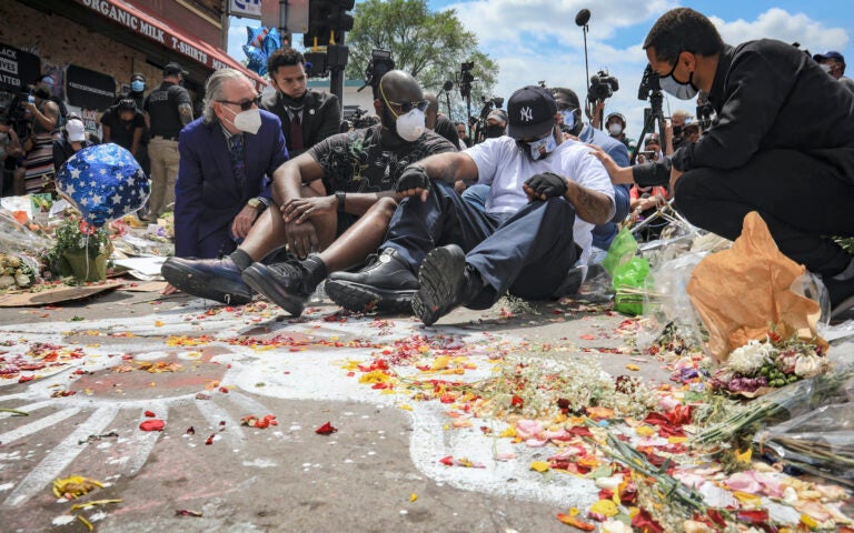 In this June 1, 2020 file photo, an emotional Terrence Floyd, second from right, is comforted as he sits at the spot at the intersection of 38th Street and Chicago Avenue, Minneapolis, Minn., where his brother George Floyd, encountered police and died while in their custody. (AP Photo/Bebeto Matthews File)