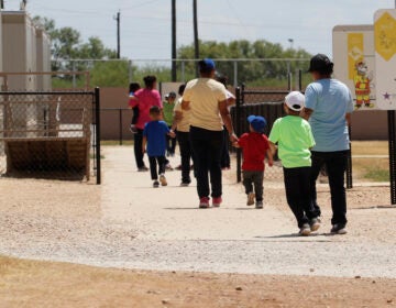 In this Aug. 23, 2019 file photo, immigrants seeking asylum hold hands as they leave a cafeteria at the ICE South Texas Family Residential Center in Dilley, Texas. (AP Photo/Eric Gay, File)