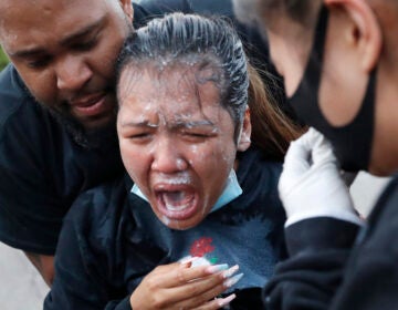 A woman is helped after being hit with pepper spray