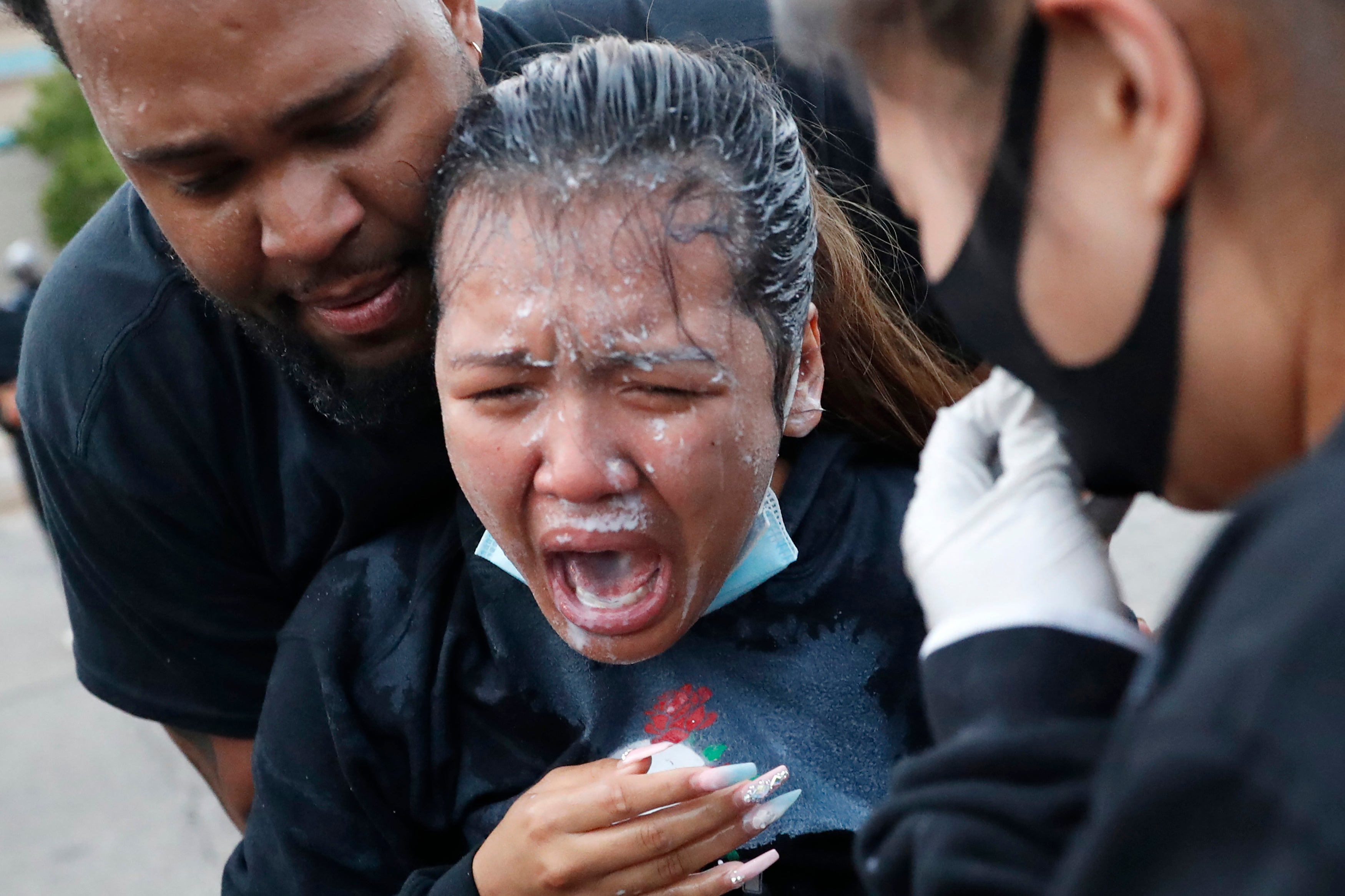 A woman is helped after being hit with pepper spray