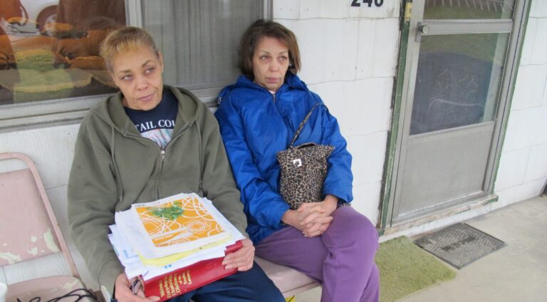 Jeanie Moten with her sister on their mother's porch in Rea, Pa. She holds a stack of medical records. The Motens say they received no help from DOH regarding their fracking health complaints. A case file released by the DOH through a Right-To-Know request confirmed that. (Susan Phillips / StateImpactPA)