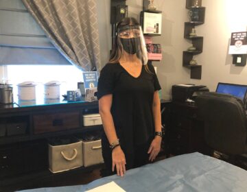Aesthetician Jen Allegretti wears the face mask and shield she will use while working with clients. (Cris Barrish/WHYY)