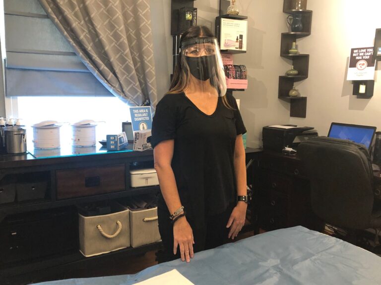 Aesthetician Jen Allegretti wears the face mask and shield she will use while working with clients. (Cris Barrish/WHYY)