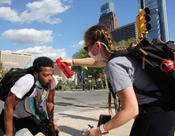 Protesters help each other after being tear-gassed on the Ben Franklin Parkway