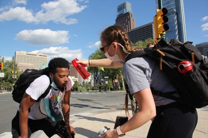 Protesters help each other after being tear-gassed on the Ben Franklin Parkway