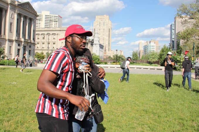 Protesters help each other after being tear gassed on the Ben Franklin Parkway. (Emma Lee/WHYY)