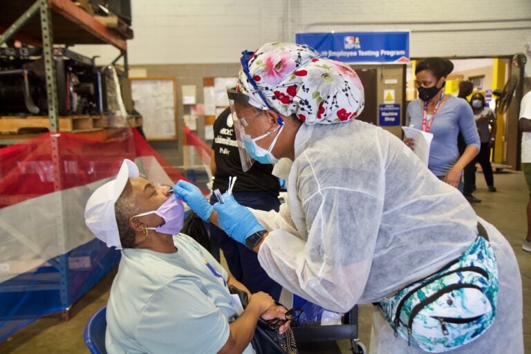 Sharon Settles, a maintenance worker, is tested for COVID-19 by Registered Nurse Cyndi Walker of the Black Doctors COVID-19 Consortium at the Fern Rock Transportation Center in Philadelphia. (Kimberly Paynter/WHYY)