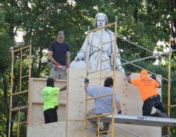 Workers box up the statue of Christopher Columbus in Marconi Plaza. (Emma Lee/WHYY)