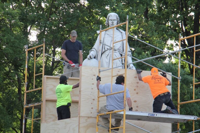 Workers box up the statue of Christopher Columbus in Marconi Plaza. (Emma Lee/WHYY)