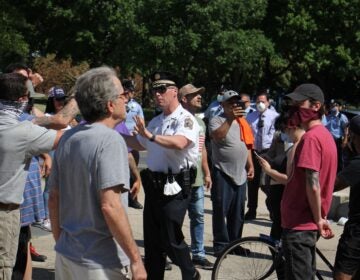 Capt. Michael O’Donnell steps between protesters as tensions rise near the statue of Christopher Columbus in Marconi Plaza. (Emma Lee/WHYY)