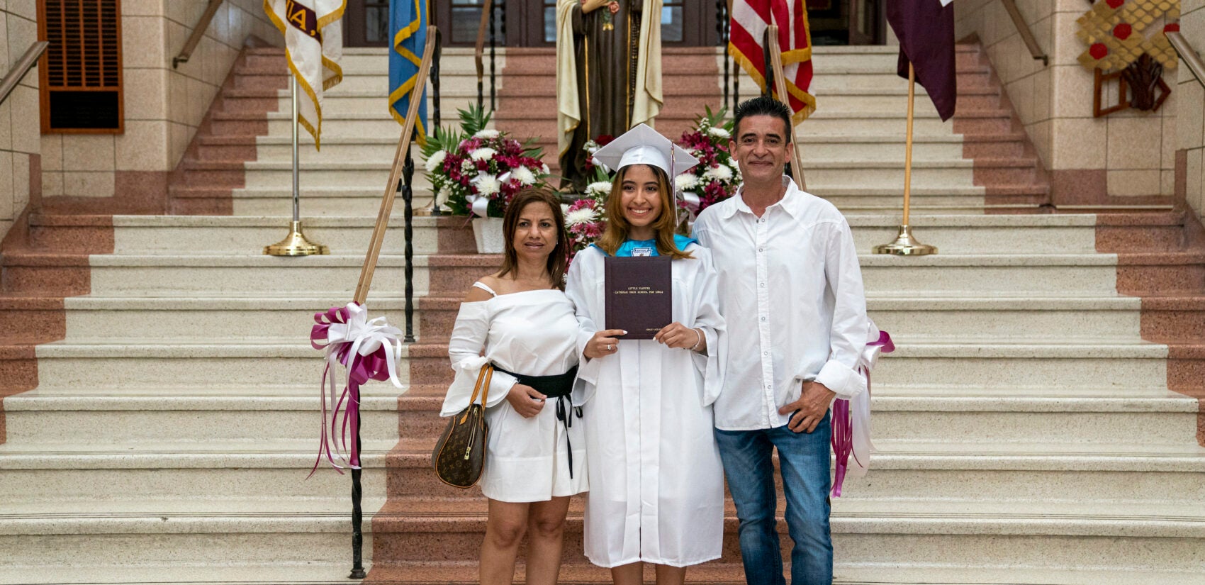 Ashley Acevedo with her parents Elena and Johnny on graduation day inside Little Flower Catholic School for Girls. (Jessica Kourkounis for Keystone Crossroads)