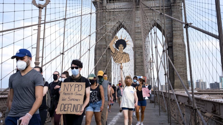 Protesters and activists walk across the Brooklyn Bridge Saturday in New York. Cities saw some of their biggest gatherings of the past two weeks on Saturday.