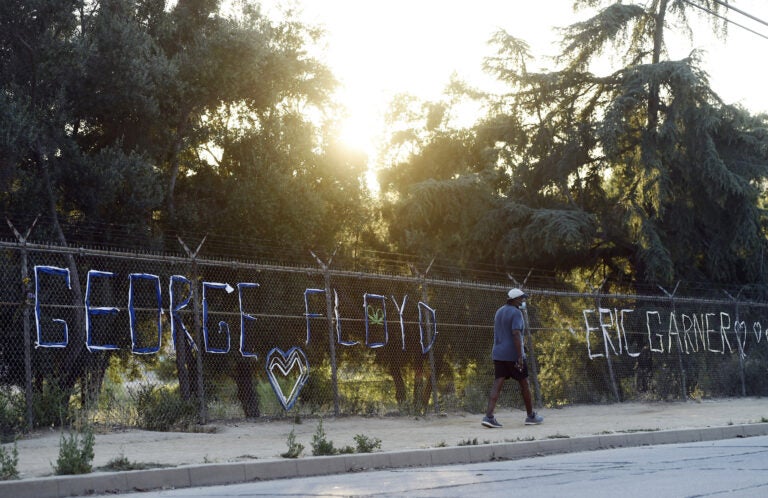 A walker passes by the names of George Floyd and Eric Garner spelled out in fabric at the art installation 