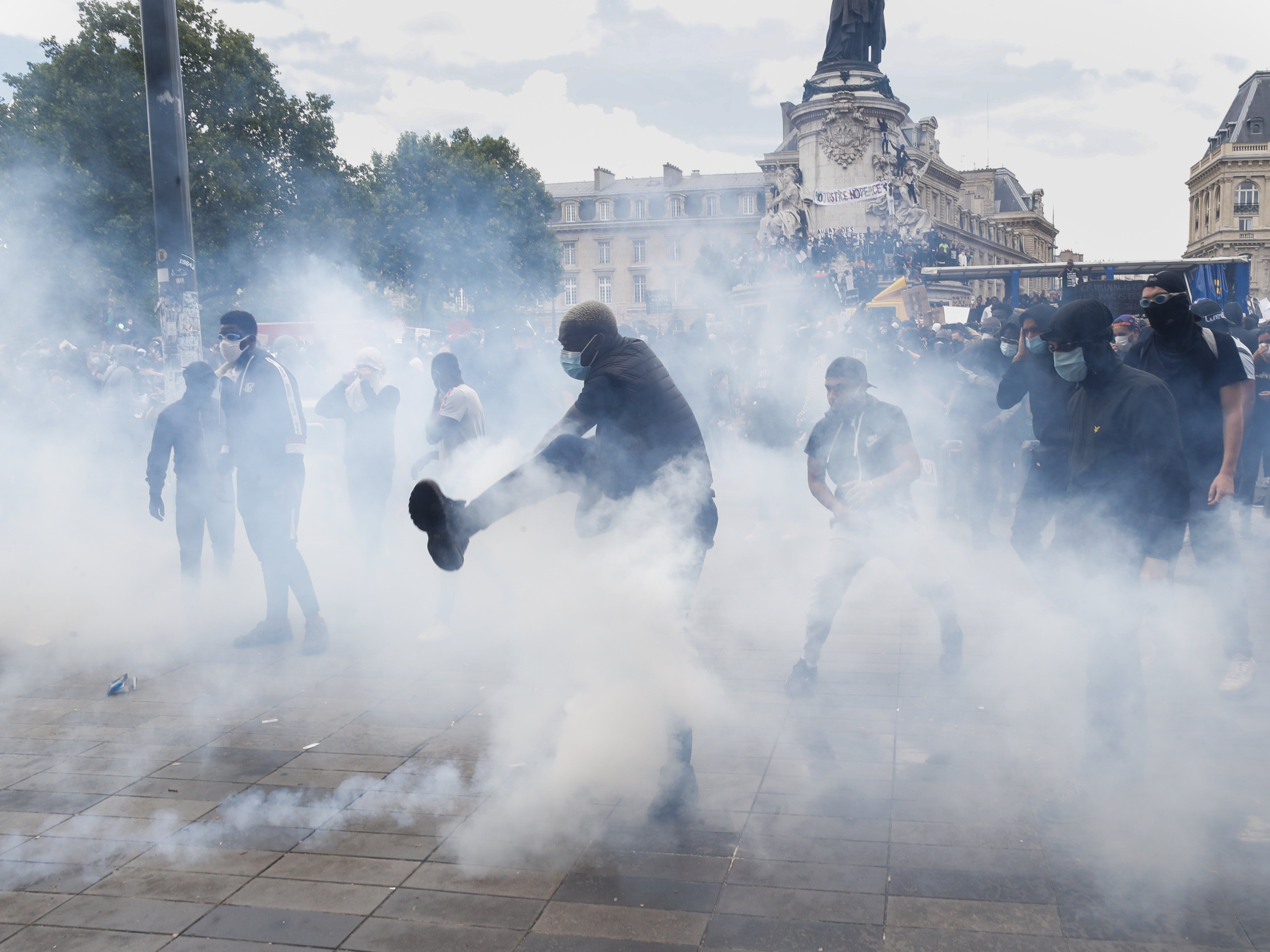 A man kicks a tear gas canister during a march against police brutality and racism in Paris.