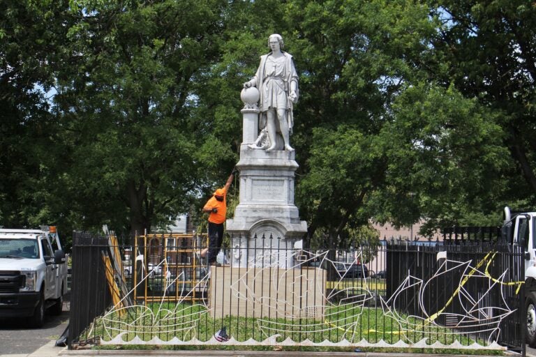 A worker measures the Christopher Columbus statue at Marconi Plaza