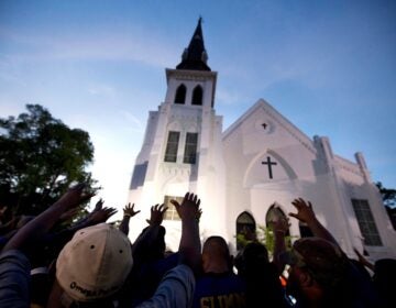 In this June 19, 2015, file photo, the men of Omega Psi Phi Fraternity Inc. lead a crowd of people in prayer outside the Emanuel AME Church, after a memorial service for the nine people killed by Dylann Roof in Charleston, S.C. (Stephen B. Morton/AP)