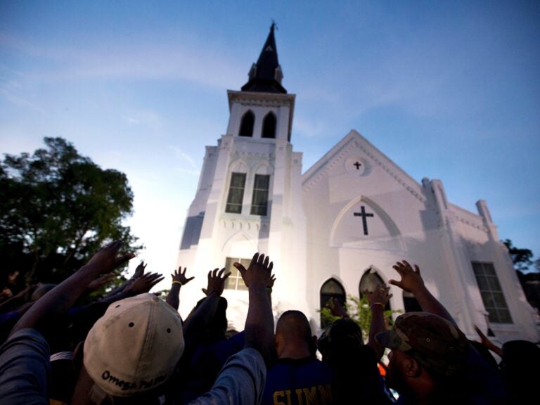 In this June 19, 2015, file photo, the men of Omega Psi Phi Fraternity Inc. lead a crowd of people in prayer outside the Emanuel AME Church, after a memorial service for the nine people killed by Dylann Roof in Charleston, S.C. (Stephen B. Morton/AP)