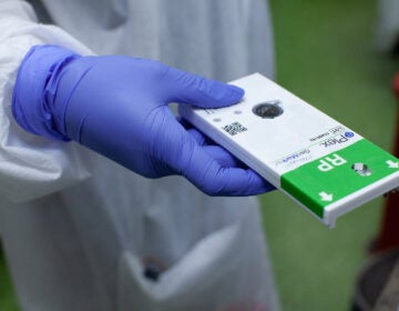 A nurse prepares to process a COVID-19 testing kit for results. (Eman Mohammed/NPR)