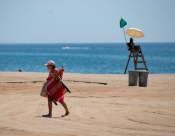 A woman walks past a lifeguard on a beach in Lloret de Mar this week, as beaches in Spain reopen following a lockdown to stop the spread of the coronavirus. The EU is now considering which countries should be allowed to send tourists to its member nations.