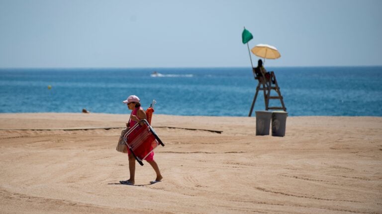 A woman walks past a lifeguard on a beach in Lloret de Mar this week, as beaches in Spain reopen following a lockdown to stop the spread of the coronavirus. The EU is now considering which countries should be allowed to send tourists to its member nations.
