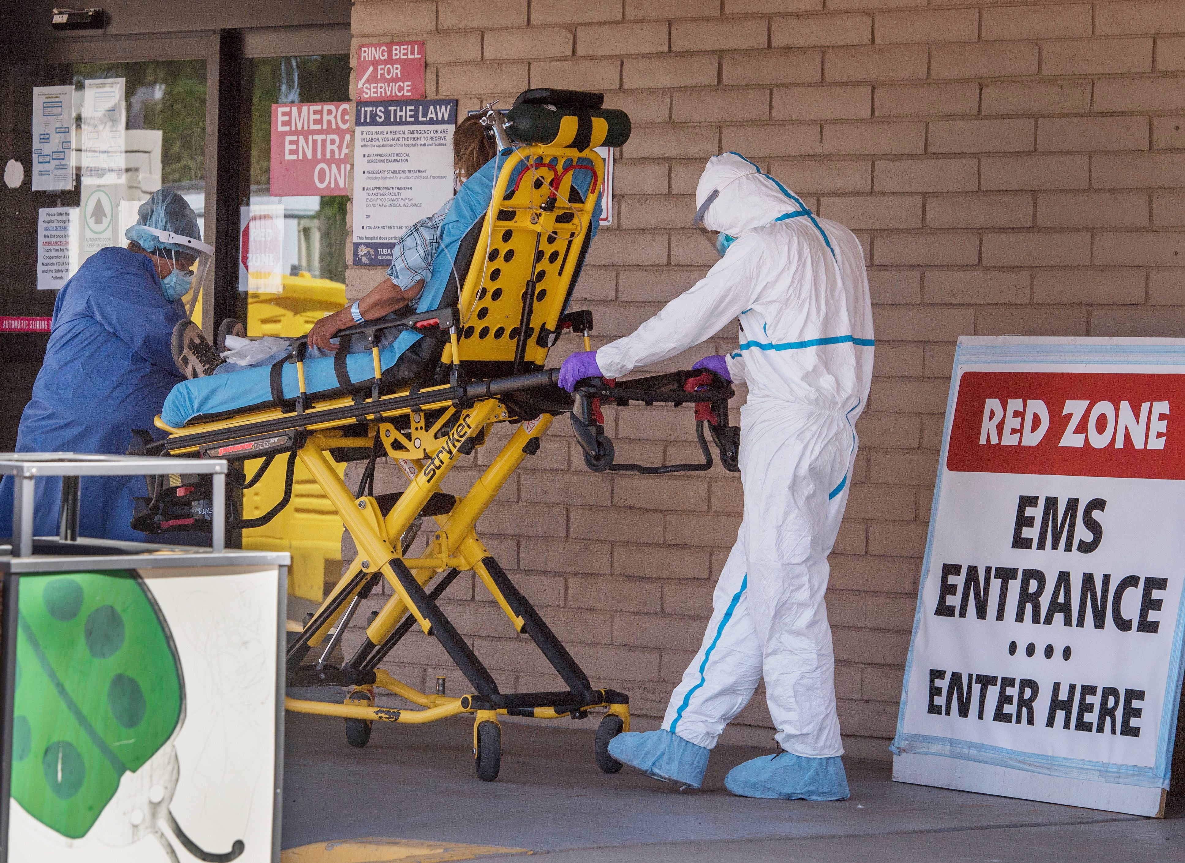 A patient is taken from an ambulance to the emergency room of a hospital in the Navajo Nation town of Tuba City, Ariz., on May 24. Weeks of delays in delivering vital coronavirus aid to Native American tribes exacerbated the outbreak, according to Navajo Nation President Jonathan Nez.