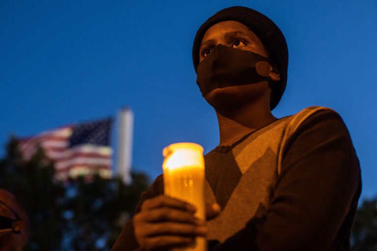 A man holds a candle during a vigil around a makeshift memorial at the tree where Robert Fuller was found dead hanging from a rope in Palmdale, Calif. Officials deemed Fuller's death a suicide, but his family wants an independent investigation.