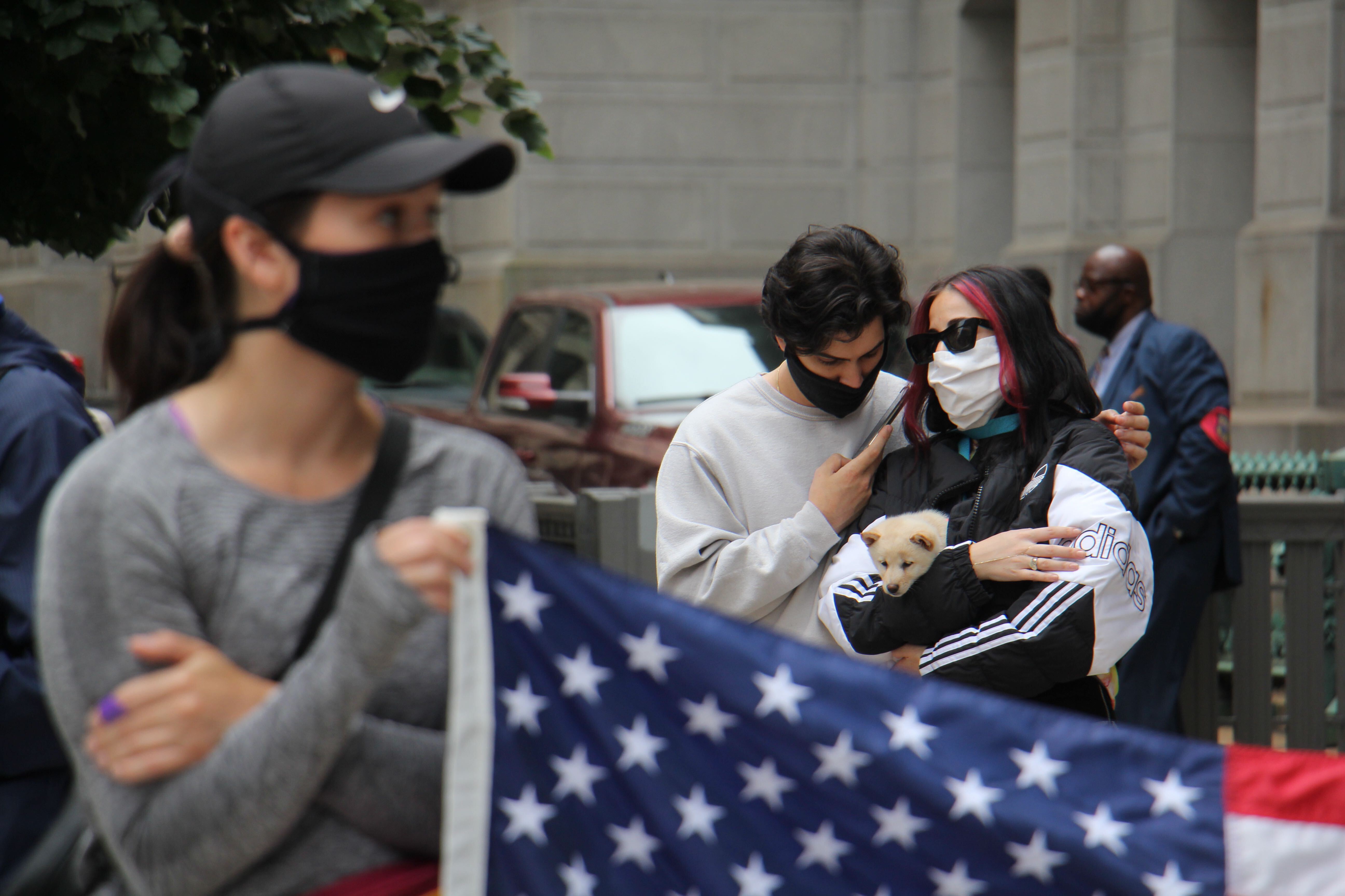 Cameron and Nina Fatholahi of Philadelphia listen to Joe Biden’s speech outside City Hall, while Nina cradles an 8-week-old puppy, Penny Lane.