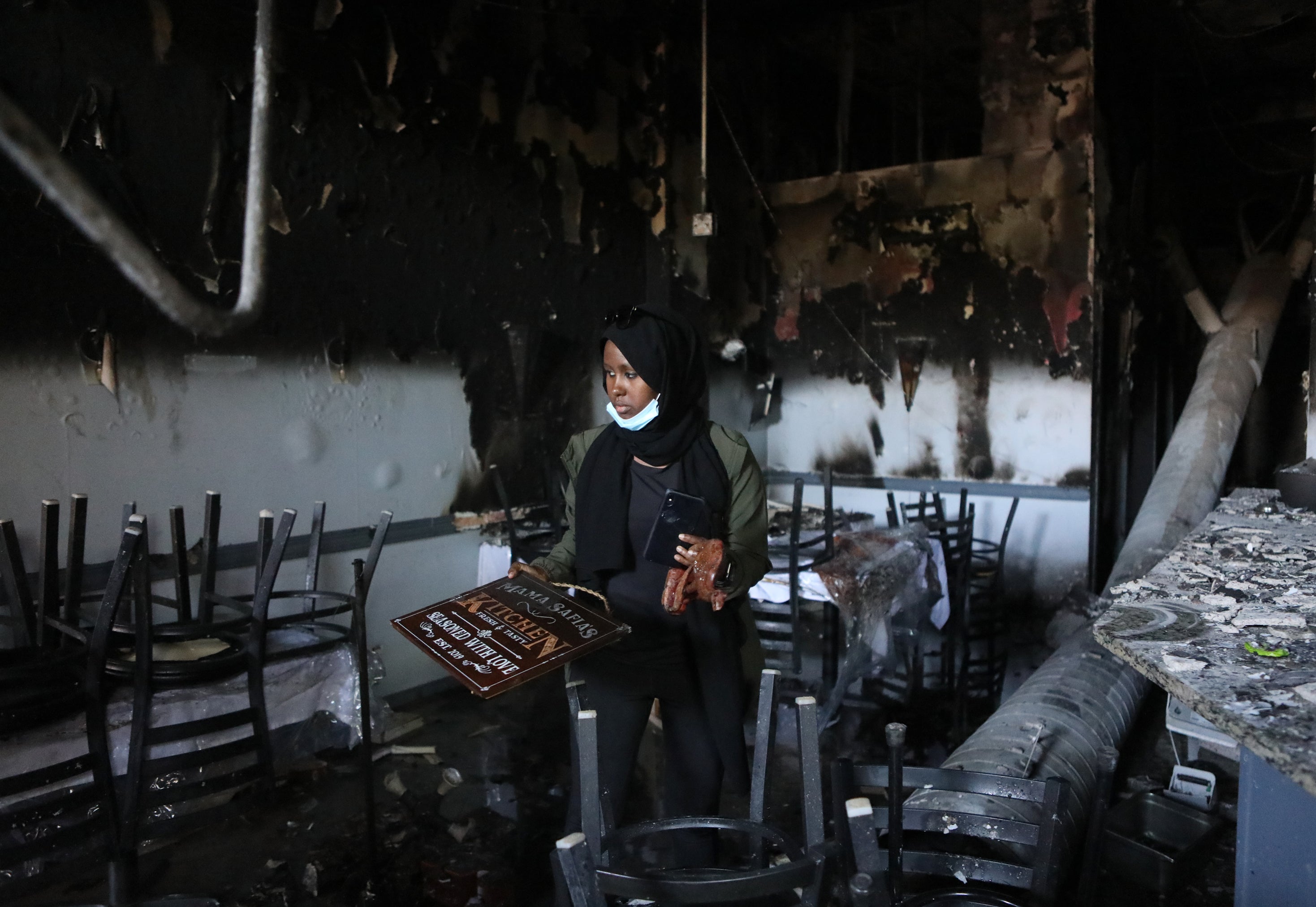 Saida Hassan looks over the remains of her mother's restaurant, Mama Safia's Kitchen, on Saturday. She doesn't want destruction, but says, "people are crying for help."
