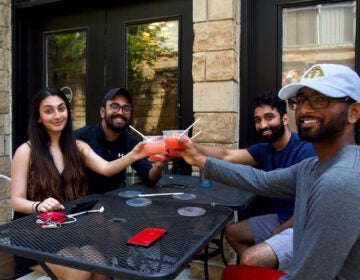 Rayyan Aziz (front left), Joel James (back left), Ravi Patel (back right) and Sean Shaji (front right) toast with margaritas at Set NoLibs outdoor seating. Today is the first day outdoor dining is allowed since coronavirus shutdowns. (Kimberly Paynter/WHYY)