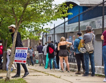 Voters wait in a socially distanced line outside their polling place