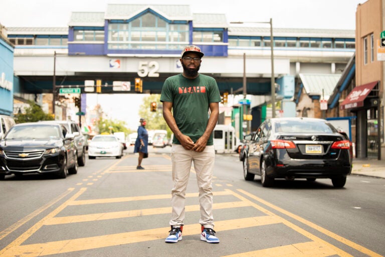 James Aye, a youth organizer, stands in the median on 52nd Street. (Ryan M. Collerd for PlanPhilly)