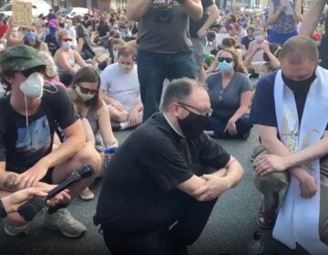 Two members of clergy who are not with POWER say a prayer in Fishtown. (Katie Meyer/WHYY)