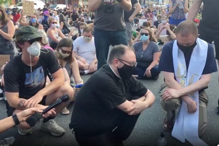 Two members of clergy who are not with POWER say a prayer in Fishtown. (Katie Meyer/WHYY)