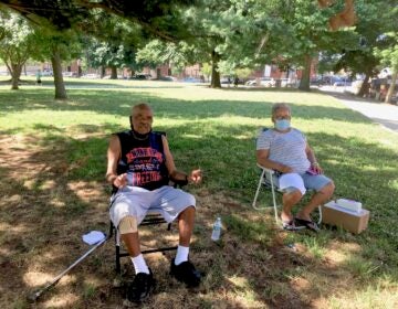 Gilberto Padilla, 78, and Carmen Román, 70, set up their chairs in the shade in Norris Square to beat the heat. (Catalina Jaramillo/WHYY)