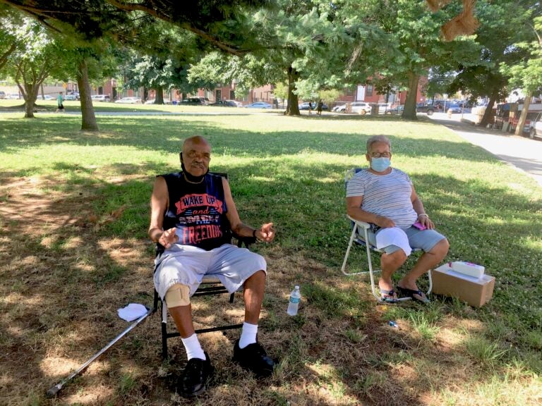 Gilberto Padilla, 78, and Carmen Román, 70, set up their chairs in the shade in Norris Square to beat the heat. (Catalina Jaramillo/WHYY)