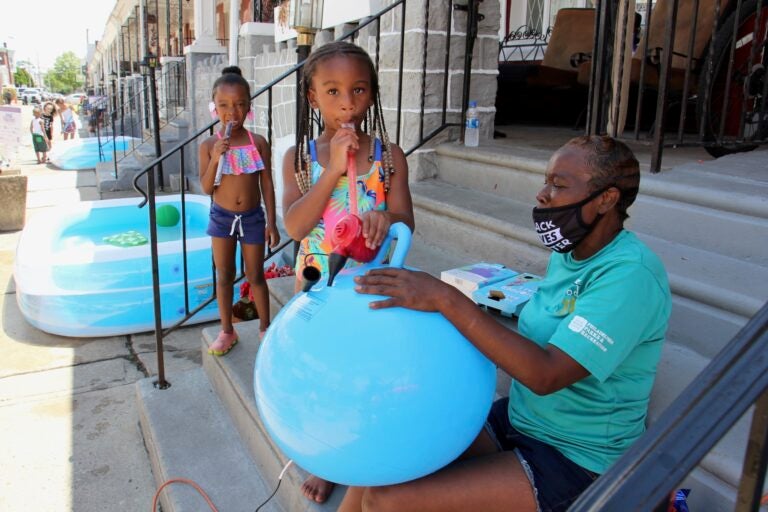 Taylor Corbin, 4, (center) helps block captain Roslyn Myers inflate a hopper ball