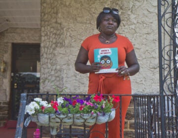 Kimberly Kamara holds a children’s book she wrote to help explain to her grandson how his father’s life ended tragically. (Kimberly Paynter/WHYY)