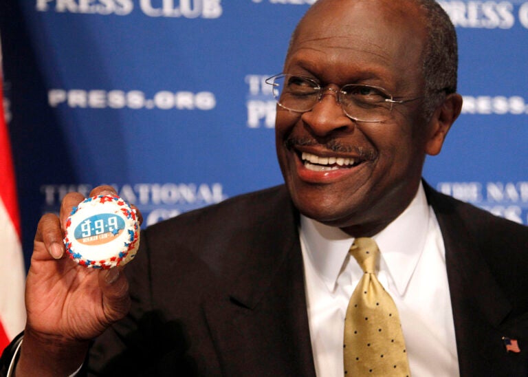 In this Oct. 31, 2011 file photo, then-Republican presidential candidate Herman Cain holds up a muffin that has his catch-phrase 9-9-9 tax plan printed on it  before speaking at the National Press Club in Washington. (AP Photo/Pablo Martinez Monsivais)