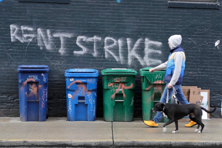 A pedestrian walks past graffiti that reads 