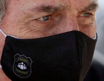 FILE - In this May 26, 2020 file photo, Brazil's President Jair Bolsonaro, wearing a face mask with a logo of the Federal Police, leaves his official residence of Alvorada Palace in Brasilia, Brazil.  (AP Photo/Eraldo Peres, FIle)